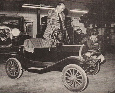 An early motor car in a workshop, from the archive
