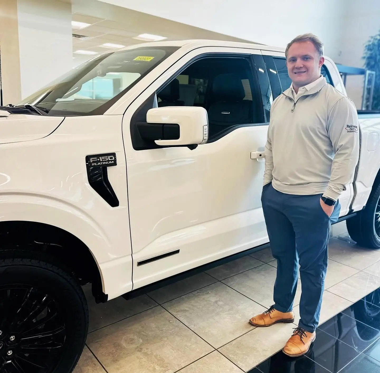 A customer beside a white Ford pickup at a Reineke dealership